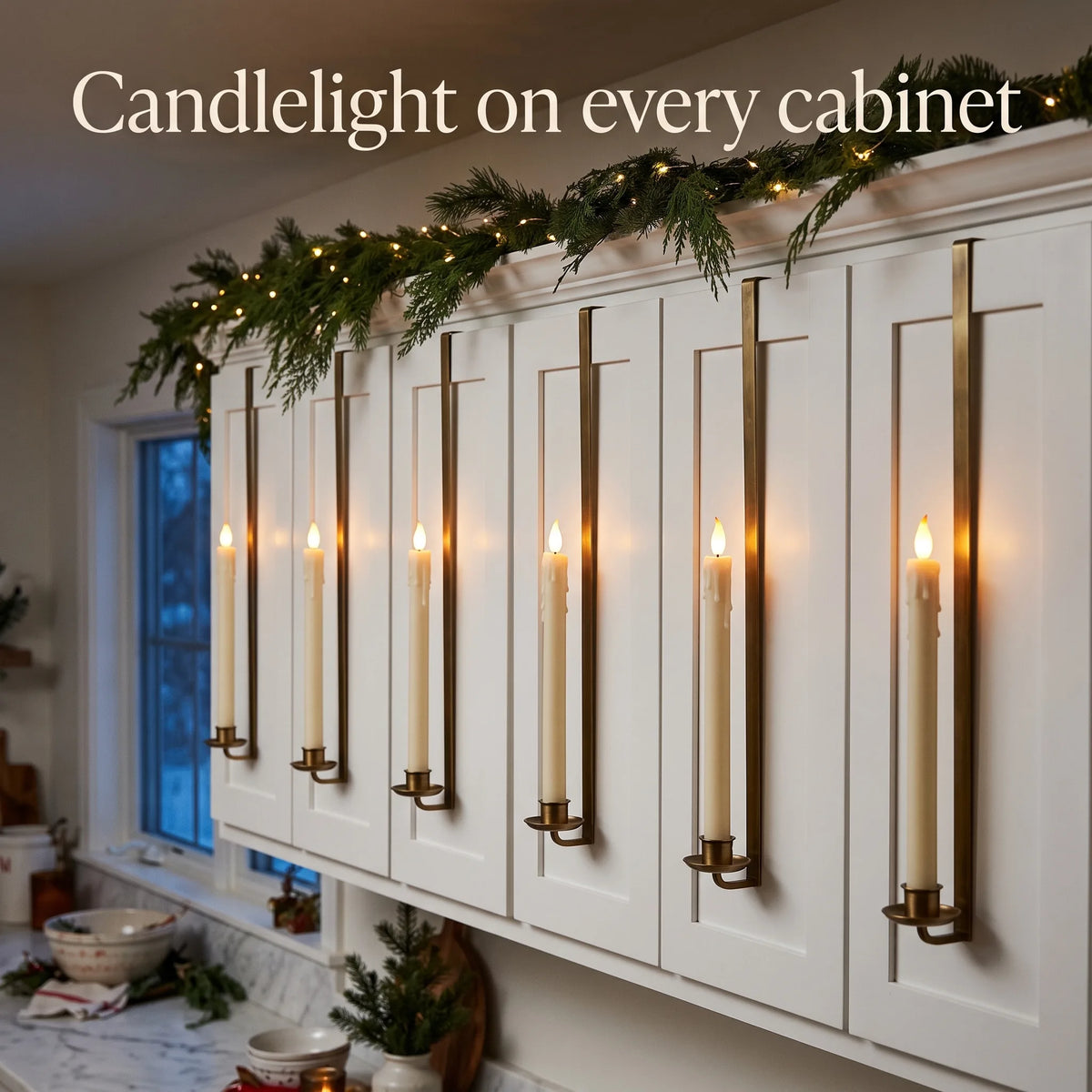 Row of LED taper candles glowing on white kitchen cabinets with Christmas garland